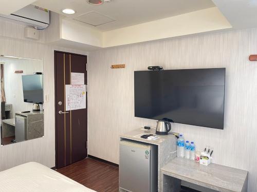 a hotel room with a large flat screen tv on the wall at Jung Shin Hotel in Zhongli