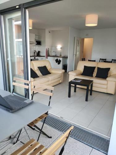 un salon avec un canapé et une table avec un ordinateur portable dans l'établissement L'Envol - 80 M2 - 40 M2 balcon - 2 parkings privés, à Toulouse
