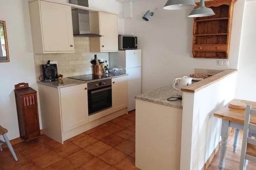 une cuisine avec des armoires blanches et un four à plaques de cuisson dans l'établissement Gite Amandier, Ferme Bel Air, Riez, à Riez