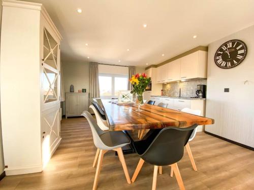 a kitchen with a wooden table and chairs and a clock at Loft Monaco - Ruime vakantieloft in De Panne