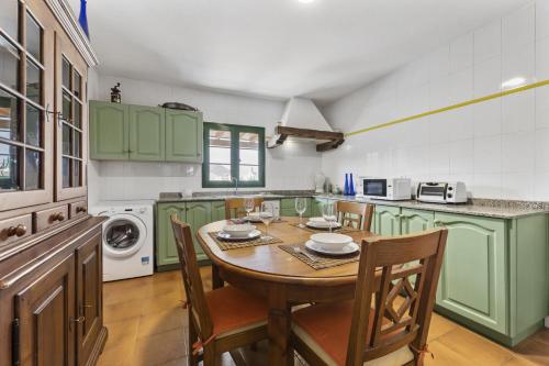 a kitchen with green cabinets and a table and chairs at Villa Laura Guatiza in Guatiza