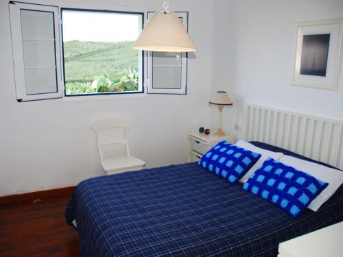 sypialnia z łóżkiem z niebieskimi poduszkami i oknem w obiekcie Villa Laura Guatiza w mieście Guatiza