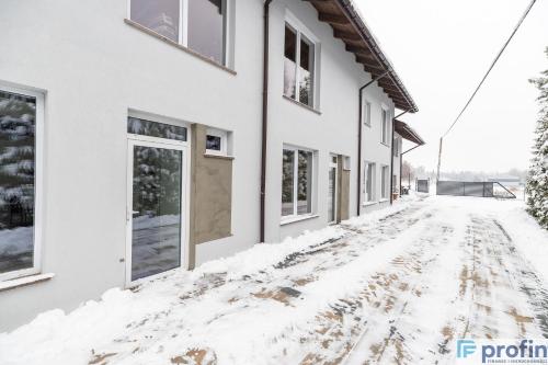 a snow covered street in front of a house at Apartamenty na Górce in Olsztyn