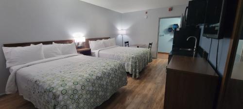 a hotel room with two beds and a television at HomeTowne Studios by Red Roof Egg Harbor-Atlantic City Airport in Egg Harbor Township
