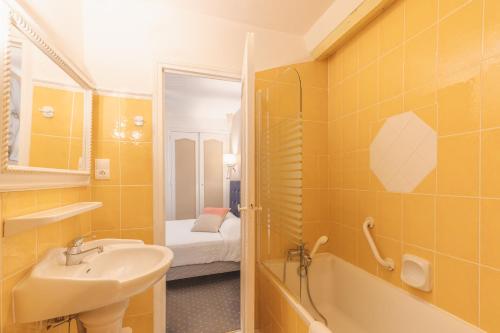 a bathroom with yellow tiles and a sink and a tub at Hostellerie du Passeur - Hôtel & Restaurant - Climatisation et Piscine chauffée in Les Eyzies-de-Tayac