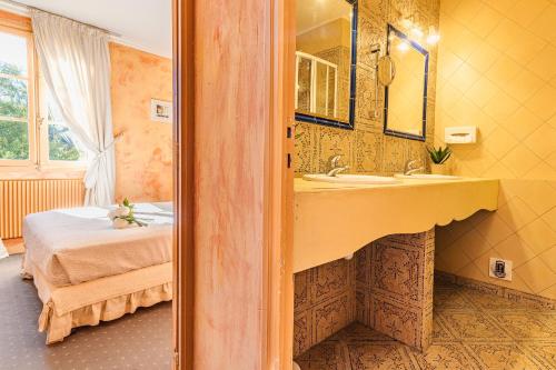 Hostellerie du Passeur - Hôtel & Restaurant - Climatisation et Piscine chauffée في ليه إيزي-دو-تاياك: حمام مع مغسلة وسرير في الغرفة