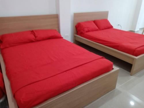 two beds with red covers in a bedroom at Apartamento para Viajeros 3 in Yabucoa