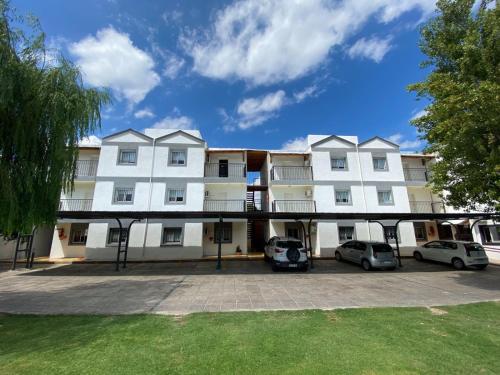 een groot wit gebouw met auto's geparkeerd op een parkeerplaats bij Apart Hotel Pueblo Viejo in San Juan
