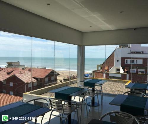 een kamer met tafels en stoelen en uitzicht op het strand bij La Mirage in Villa Gesell