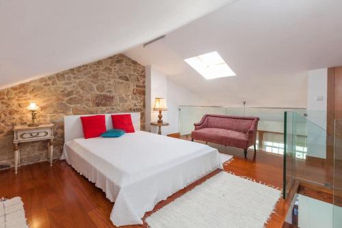a bedroom with a large bed and a red chair at Apartamentos Lumar in Valença