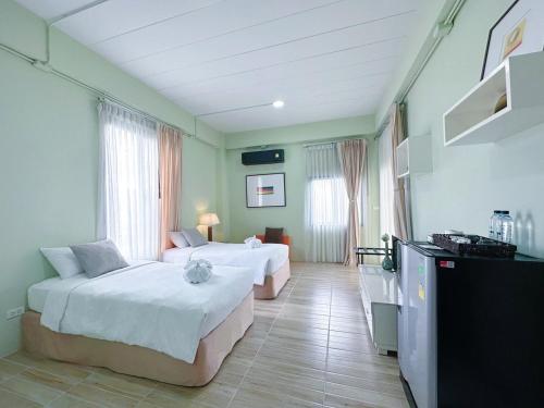 a hotel room with two beds and a television at Daddy Dream Hotel and Residence in Ranong