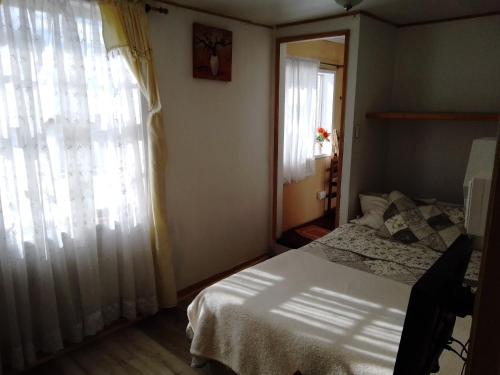 a bedroom with a bed and a large window at Hostal Patrimonial Angelmó in Puerto Montt
