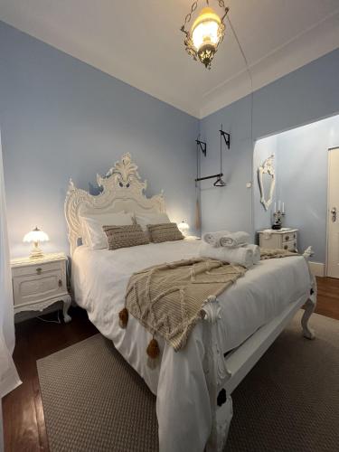 una camera da letto con un grande letto bianco e un lampadario a braccio di Casinhas no Carolina - Hostel a Porto