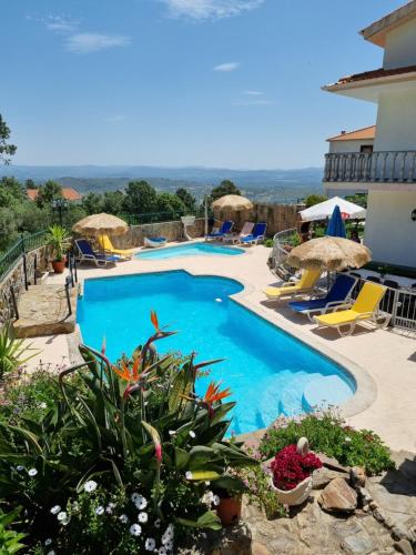 a pool with chairs and umbrellas next to a building at Quinta do Ribeiro - Covilhã - Serra da Estrela in Covilhã