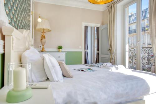 a bedroom with a large white bed with a window at Marais Appart Haussmannien Neuf Clim & Ascenseur in Paris