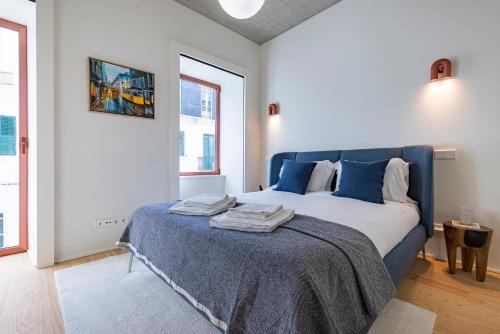 a bedroom with a large bed with blue pillows at Deluxe 2BDR Apartment W/ Patio by LovelyStay in Lisbon
