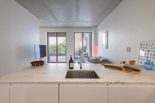 a kitchen with a sink and a living room at Deluxe 2BDR Apartment W/ Patio by LovelyStay in Lisbon