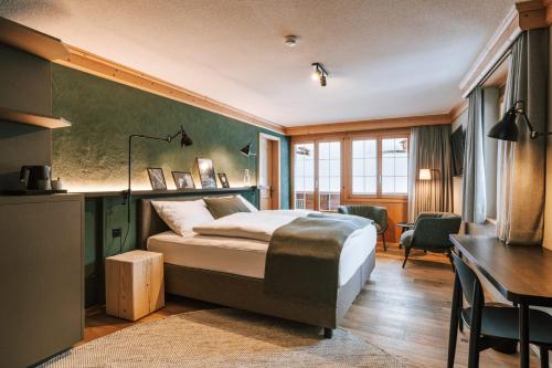Habitación de hotel con cama, escritorio y mesa. en Hotel Fiescherblick en Grindelwald