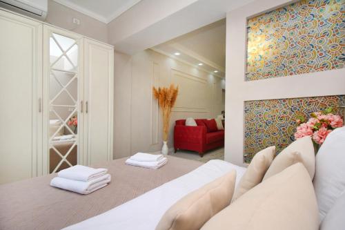 1 dormitorio con cama blanca y sofá rojo en Уютная студия на Арбате, en Almaty