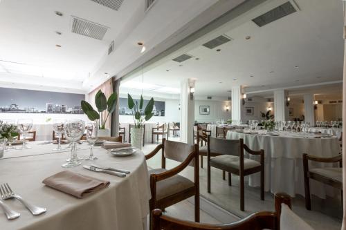 uma sala de jantar com mesas e cadeiras brancas em Feir's Park Hotel & Rooftop em Buenos Aires