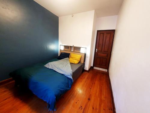 a bedroom with a bed with blue sheets and yellow pillows at La ruelle des 2 vallées in Arreau
