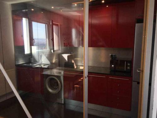 a kitchen with red cabinets and a washing machine at Loft estilo industrial a 5 minutos del centro in Valladolid
