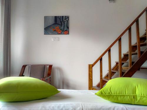 a bedroom with a bed with green pillows and a staircase at MANUDI Glenfallsedge Rest in Nuwara Eliya