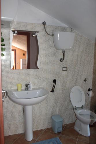 een badkamer met een wastafel, een toilet en een spiegel bij Olmedo Casa Vacanze in Olmedo