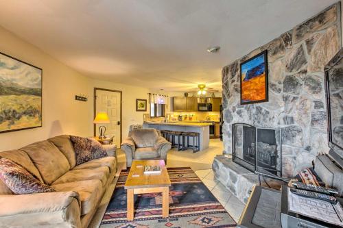 a living room with a stone wall with a fireplace at New Mexico Condo with Fireplace and Mountain View in Angel Fire