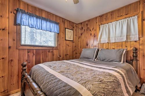 a bedroom with a bed with wooden walls and a window at Serene Woodruff Cottage Lakefront Access! in Woodruff