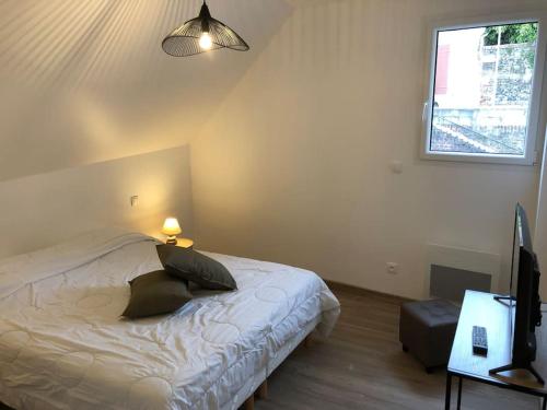 ein Schlafzimmer mit einem Bett und einem Fernseher und einem Fenster in der Unterkunft Le Lodge de Louise, centre ville Saint Valery sur somme in Saint-Valery-sur-Somme