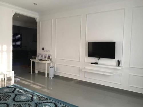 a white living room with a flat screen tv at Inap Singgah Homestay in Kota Bharu