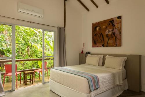 a bedroom with a bed and a sliding glass door at Hotel Boutique Ananas in Ilhabela