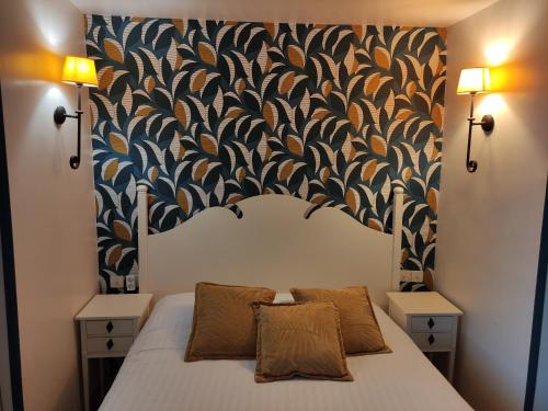 a bed with two pillows in a bedroom with a wallpaper at Le Pavillon Saint-Martin in Souillac