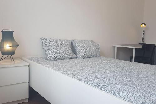 a bedroom with a bed with a night stand and a lamp at Audun-Le-Tiche - Appartements 3 chambres in Audun-le-Tiche