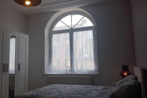 a bedroom with a large window and a bed at Audun-Le-Tiche - Appartements 3 chambres in Audun-le-Tiche