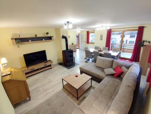 a living room with a couch and a tv at Les Randogodilleurs avec Jacuzzi à 2kms des pistes et 350m du Théatre du Peuple ! in Bussang
