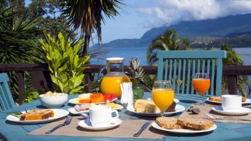 a table with breakfast food and orange juice on it at Hotel Boutique Ananas in Ilhabela