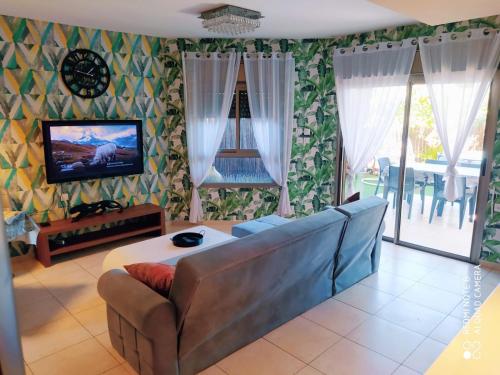 Apartment Amdar Village with garden في إيلات: غرفة معيشة مع أريكة وتلفزيون