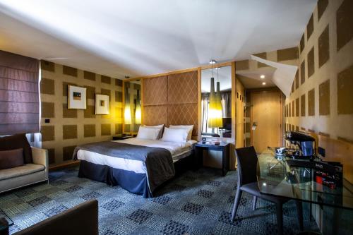 ボンヌ・シュル・ムノジュにあるHôtel Baud - Teritoriaのベッドとガラスのテーブルが備わるホテルルームです。