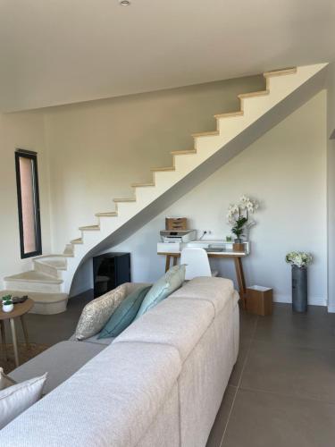 a living room with a white couch and stairs at Nid de rêves jacuzzi en Provence in Châteaurenard