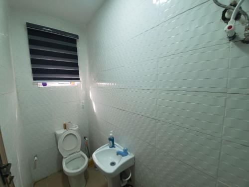 Baño blanco con aseo y lavamanos en Dinero Ruby - Studio Apartment en Lagos