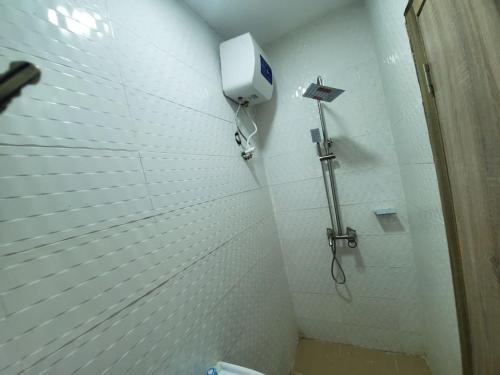 a bathroom with a shower with a phone on the wall at Dinero Ruby - Studio Apartment in Lagos