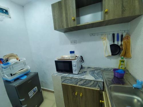 una cucina con lavello e forno a microonde su un bancone di Dinero Ruby - Studio Apartment a Lagos