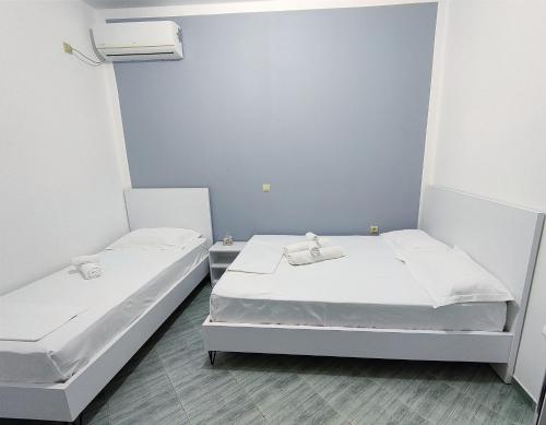 two beds in a room with white walls at Joen Apartments in Sarandë