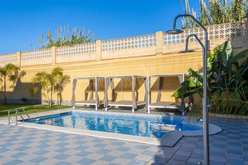 a swimming pool with chairs and a fence at Sun, Relax, Climatized Pool & Steps to the Beach by Mellow in Vélez-Málaga