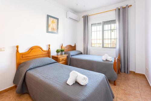 een slaapkamer met 2 bedden en handdoeken bij Sun, Relax, Climatized Pool & Steps to the Beach by Mellow in Vélez-Málaga