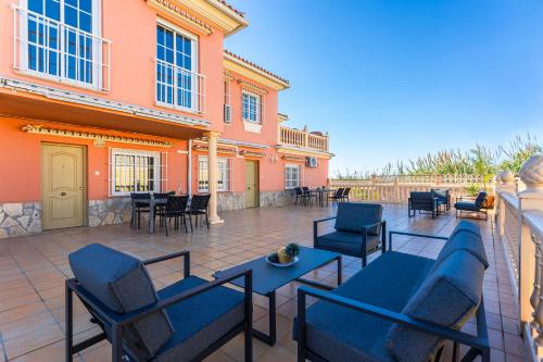 a patio with chairs and tables and a building at Sun, Relax, Climatized Pool & Steps to the Beach by Mellow in Vélez-Málaga