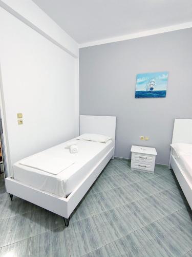 a white room with a bed and a night stand at Joen Apartments in Sarandë