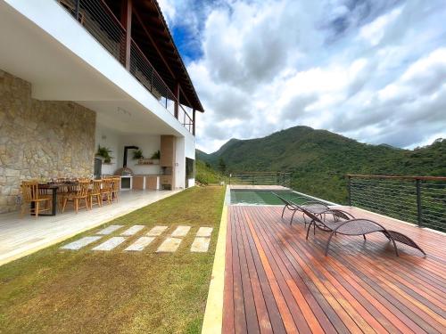 una terraza con 2 sillas y una mesa en una casa en MORADA DOS IPÊS, en Teresópolis